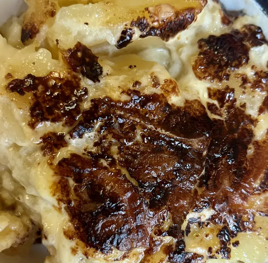 Gratin dauphinois dans une cocotte, rondelles de pommes de terre fondantes à la crème et dessus bien gratiné