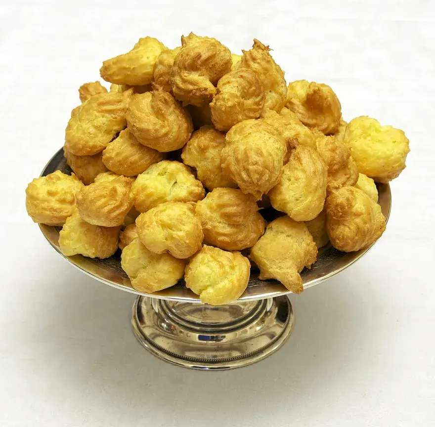 Coupe en argent remplie de petites gougères dorées au fromage