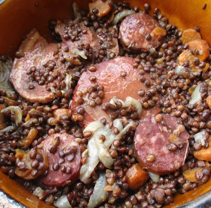 Cocotte de lentilles vertes mijotées avec des rondelles de saucisse fumée, des carottes et des oignons