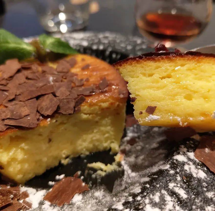 Fiadone, gâteau corse au brocciu, coupé pour montrer sa mie jaune et fondante, décoré de copeaux de chocolat