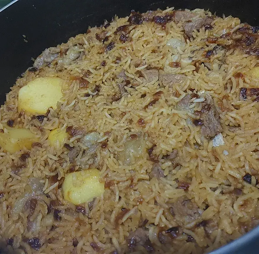 Marmite de riz pilao doré aux épices, avec des morceaux de viande et de pommes de terre