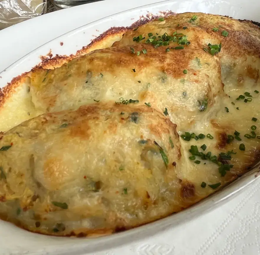 Brandade de morue gratinée dans un plat ovale blanc, dessus doré et parsemé de ciboulette