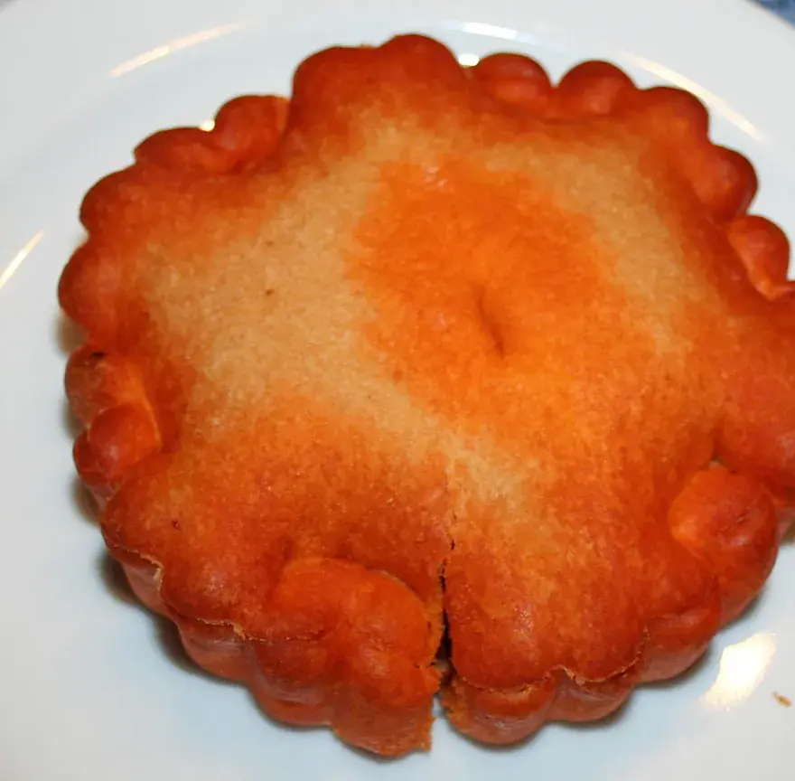 Tielle sétoise entière sur une assiette blanche, bord festonné et dessus doré et rouge à la tomate