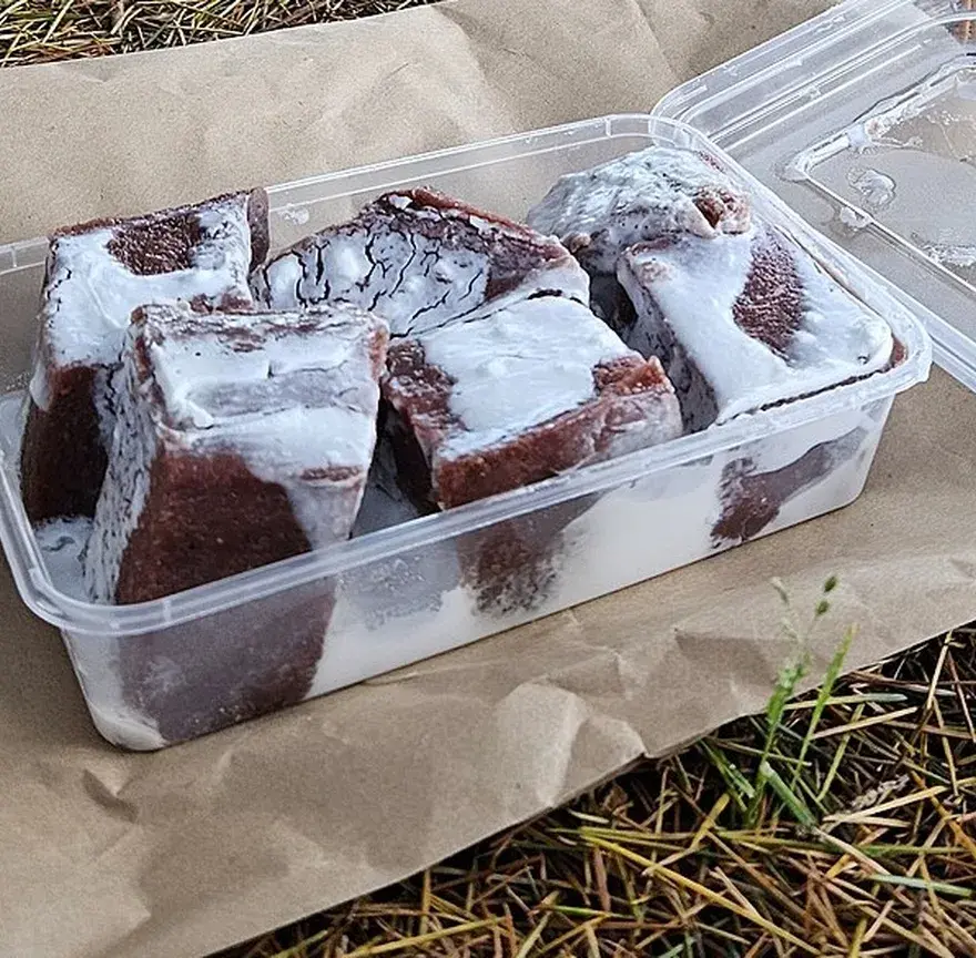 Cubes de po’e à la banane nappés de lait de coco, dans une barquette à emporter
